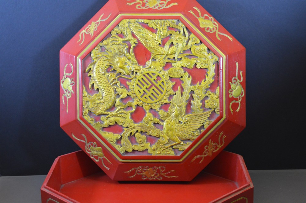 An octagonal Chinese red lacquer wedding box with relief-carved gold dragon and lotus motifs. View II