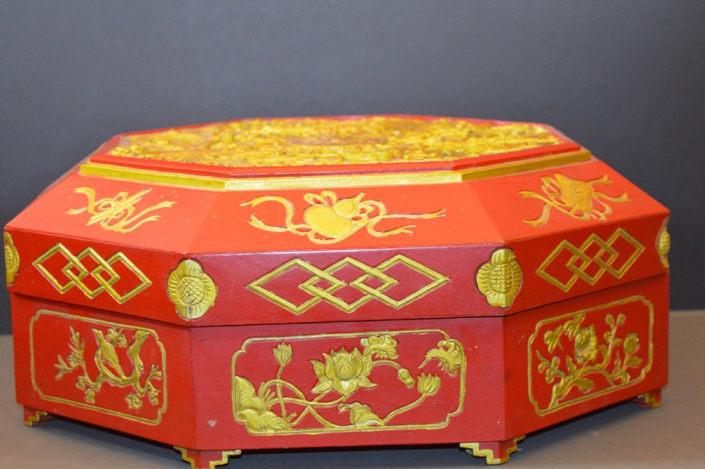 An octagonal Chinese red lacquer wedding box with relief-carved gold dragon and lotus motifs. View III