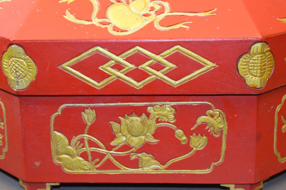 An octagonal Chinese red lacquer wedding box with relief-carved gold dragon and lotus motifs. View V