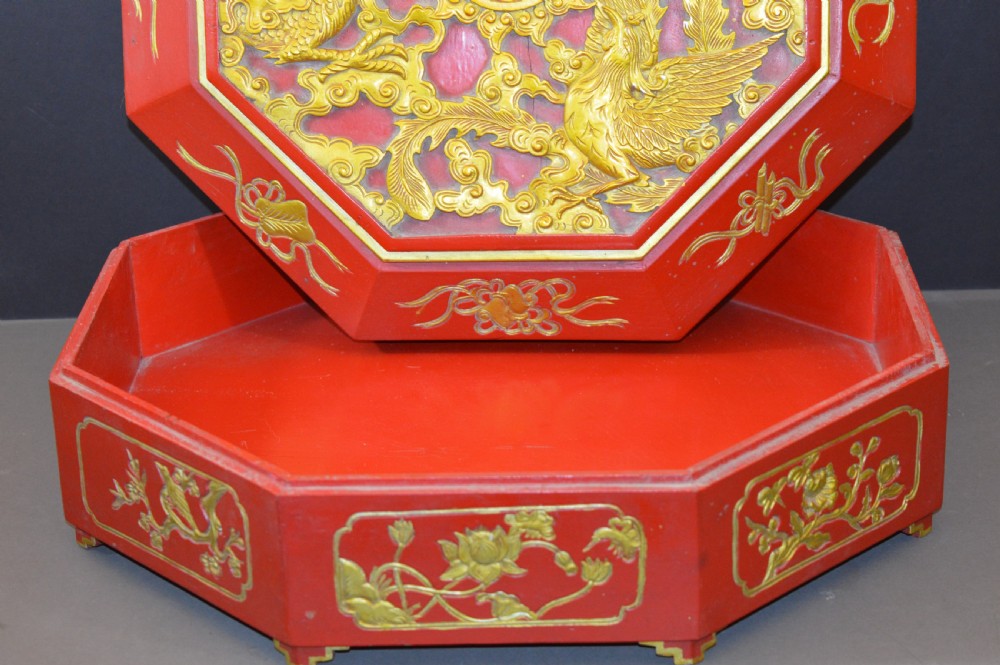 An octagonal Chinese red lacquer wedding box with relief-carved gold dragon and lotus motifs. View VIII