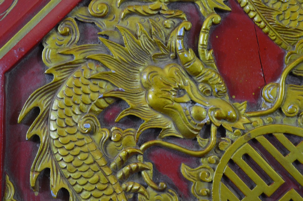 An octagonal Chinese red lacquer wedding box with relief-carved gold dragon and lotus motifs. View X