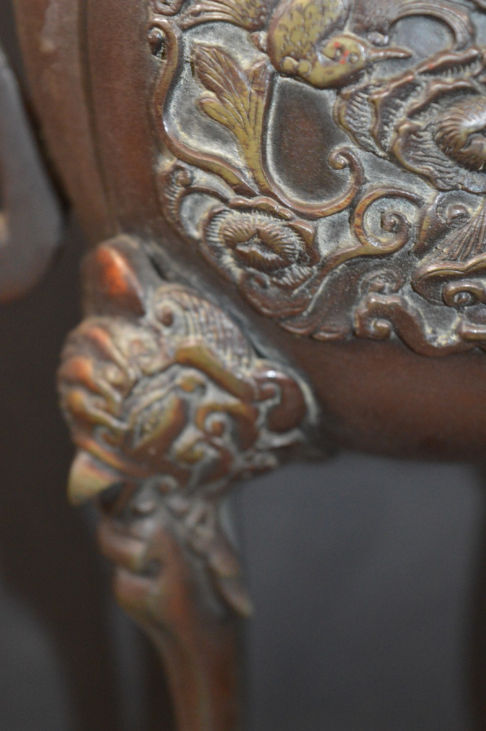 A heavy dark brown bronze Chinese incense burner featuring sculpted dragon handles, relief-carved medallions, and tall cabriole legs mounted on a round stand. View V