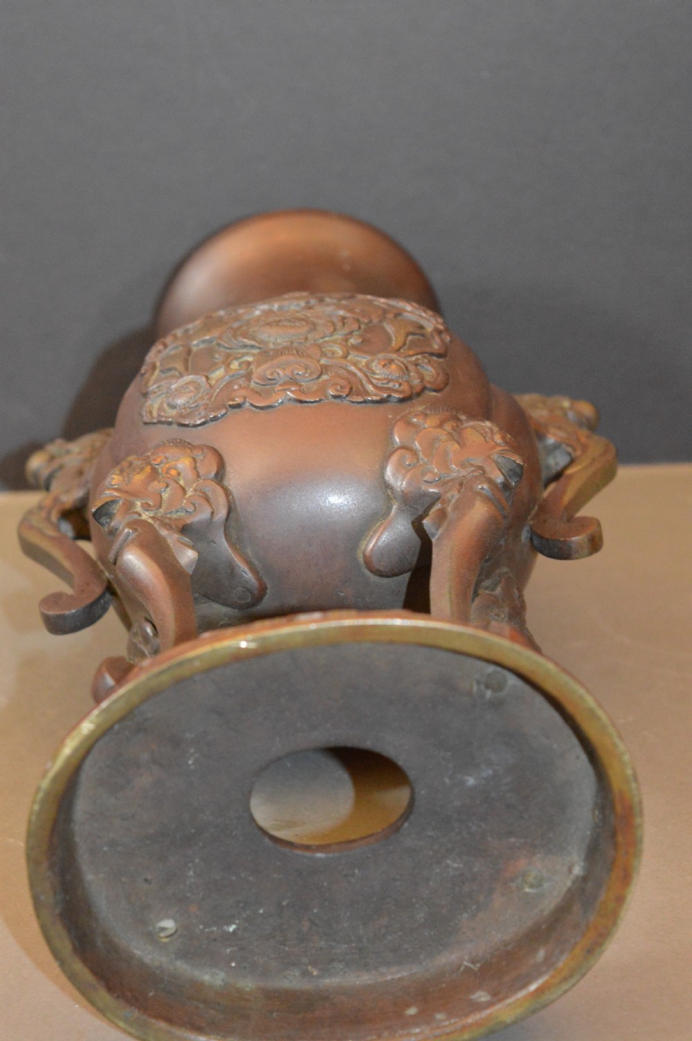 A heavy dark brown bronze Chinese incense burner featuring sculpted dragon handles, relief-carved medallions, and tall cabriole legs mounted on a round stand. View IX