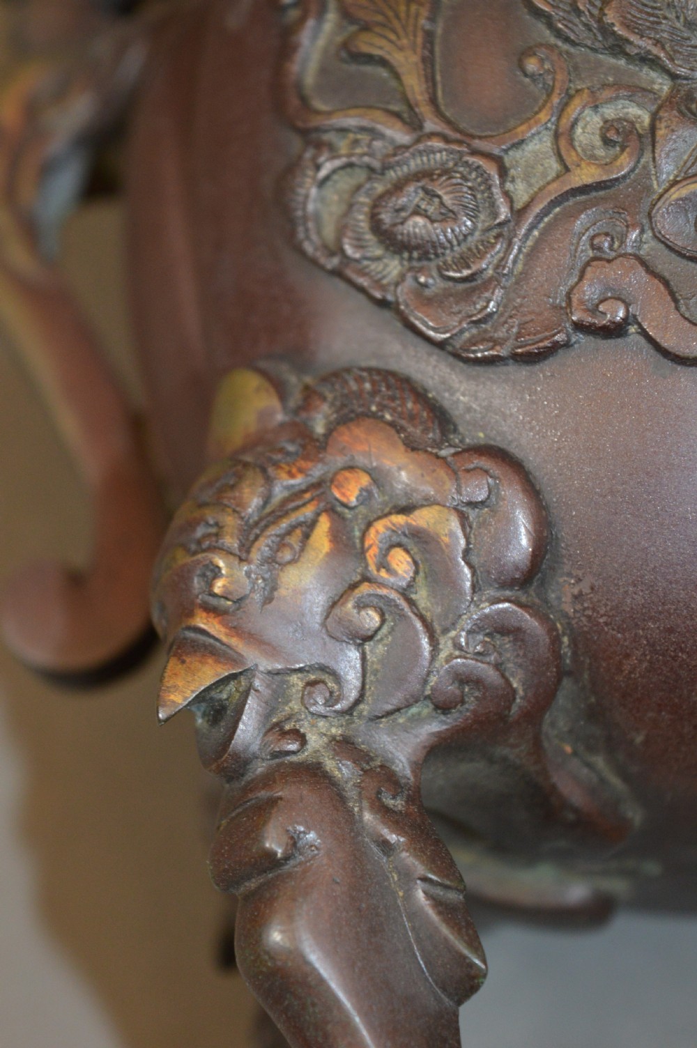 A heavy dark brown bronze Chinese incense burner featuring sculpted dragon handles, relief-carved medallions, and tall cabriole legs mounted on a round stand. View X