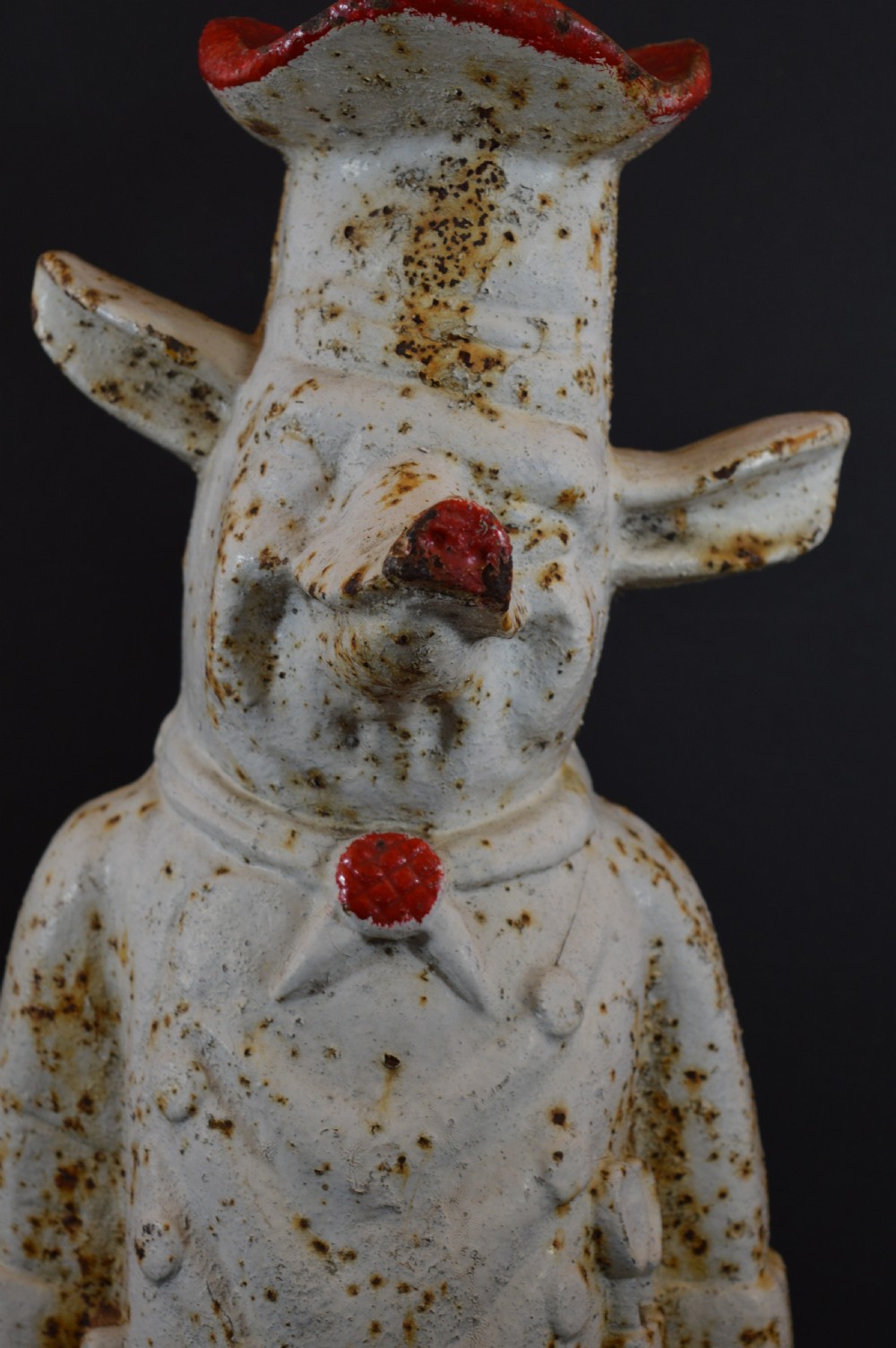 A late 19th-century cast iron figure of a pig dressed in butcher attire with distressed white paint and visible surface oxidisation. View II