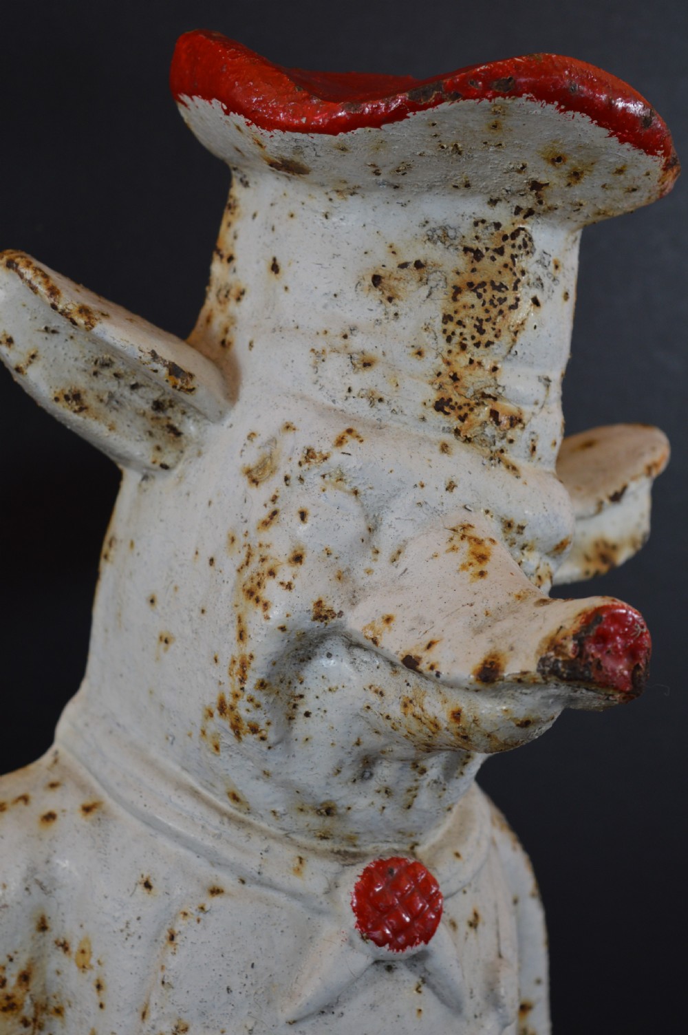 A late 19th-century cast iron figure of a pig dressed in butcher attire with distressed white paint and visible surface oxidisation. View IV