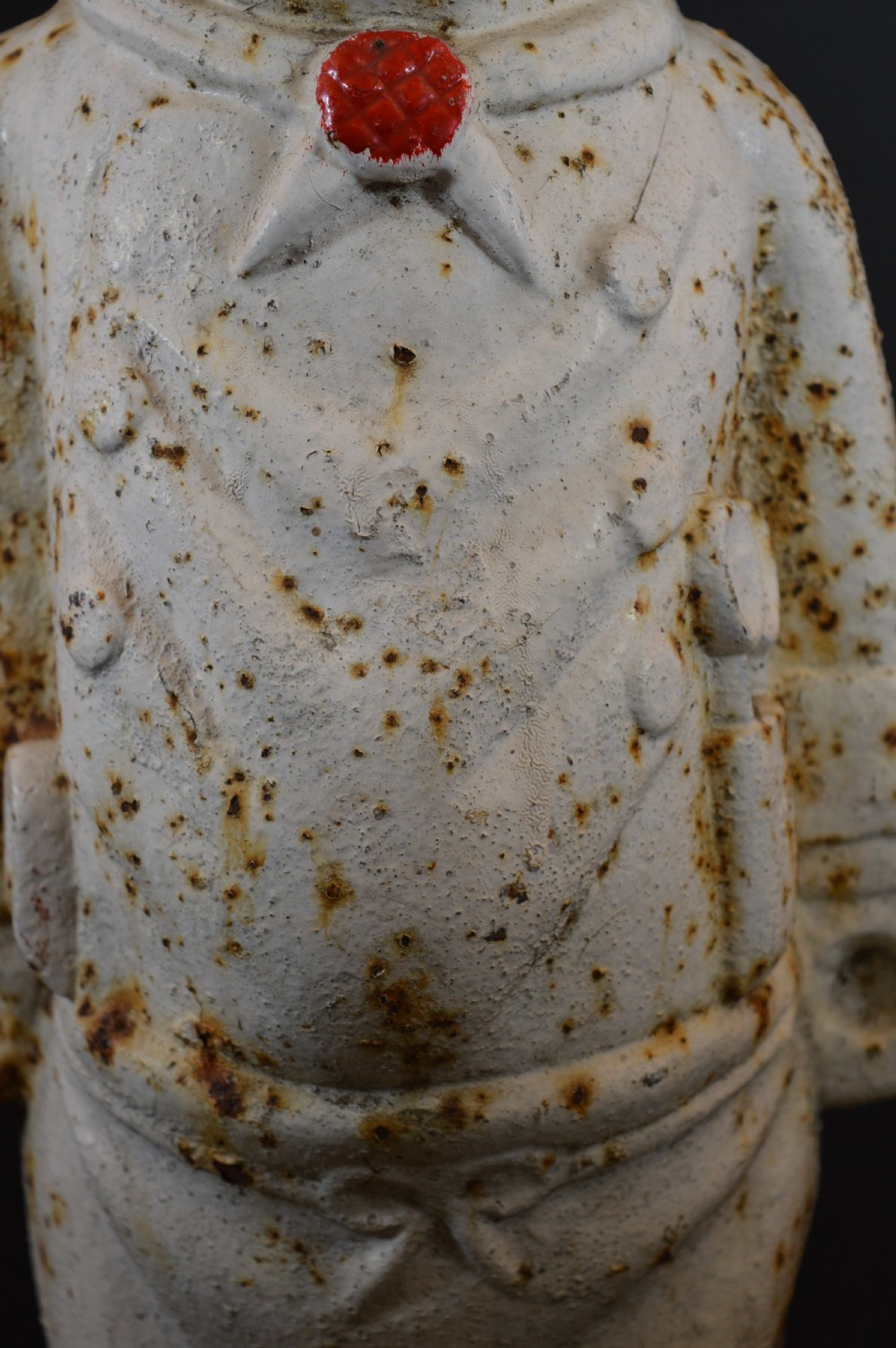 A late 19th-century cast iron figure of a pig dressed in butcher attire with distressed white paint and visible surface oxidisation. View V
