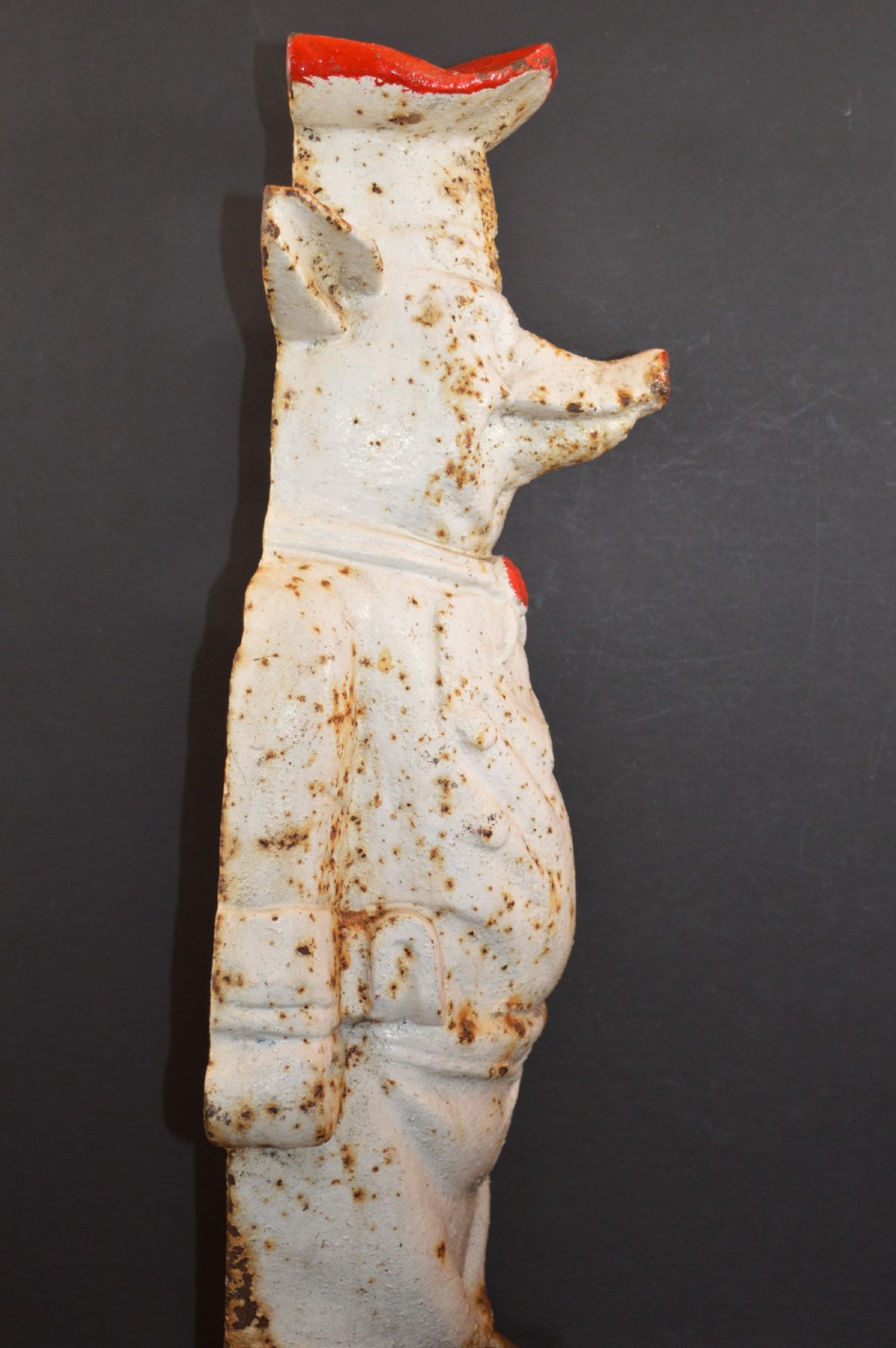 A late 19th-century cast iron figure of a pig dressed in butcher attire with distressed white paint and visible surface oxidisation. View VI