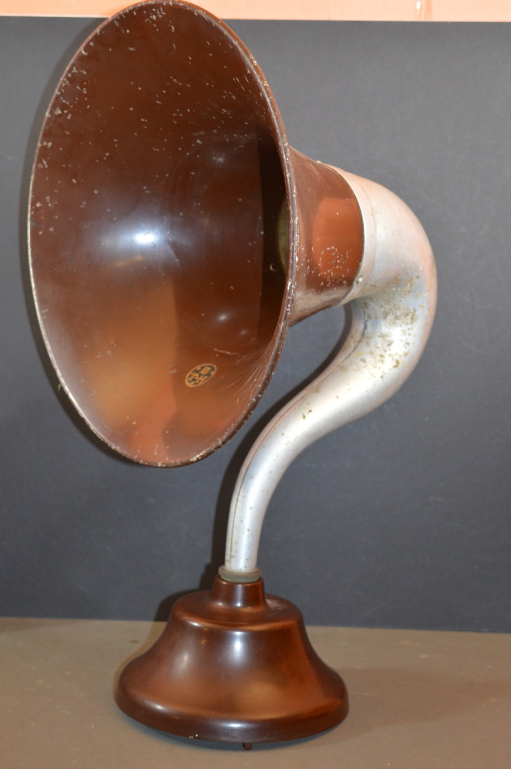An antique 1930s British Thomson-Houston horn loudspeaker with a flared dark brown Bakelite bell, a curved silver metal neck, and a matching rounded Bakelite base.