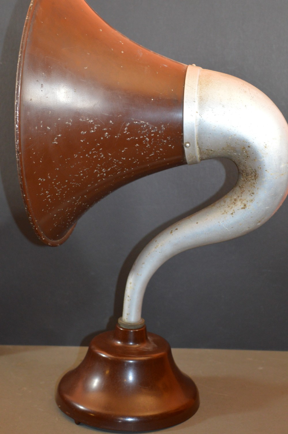 An antique 1930s British Thomson-Houston horn loudspeaker with a flared dark brown Bakelite bell, a curved silver metal neck, and a matching rounded Bakelite base. View VII