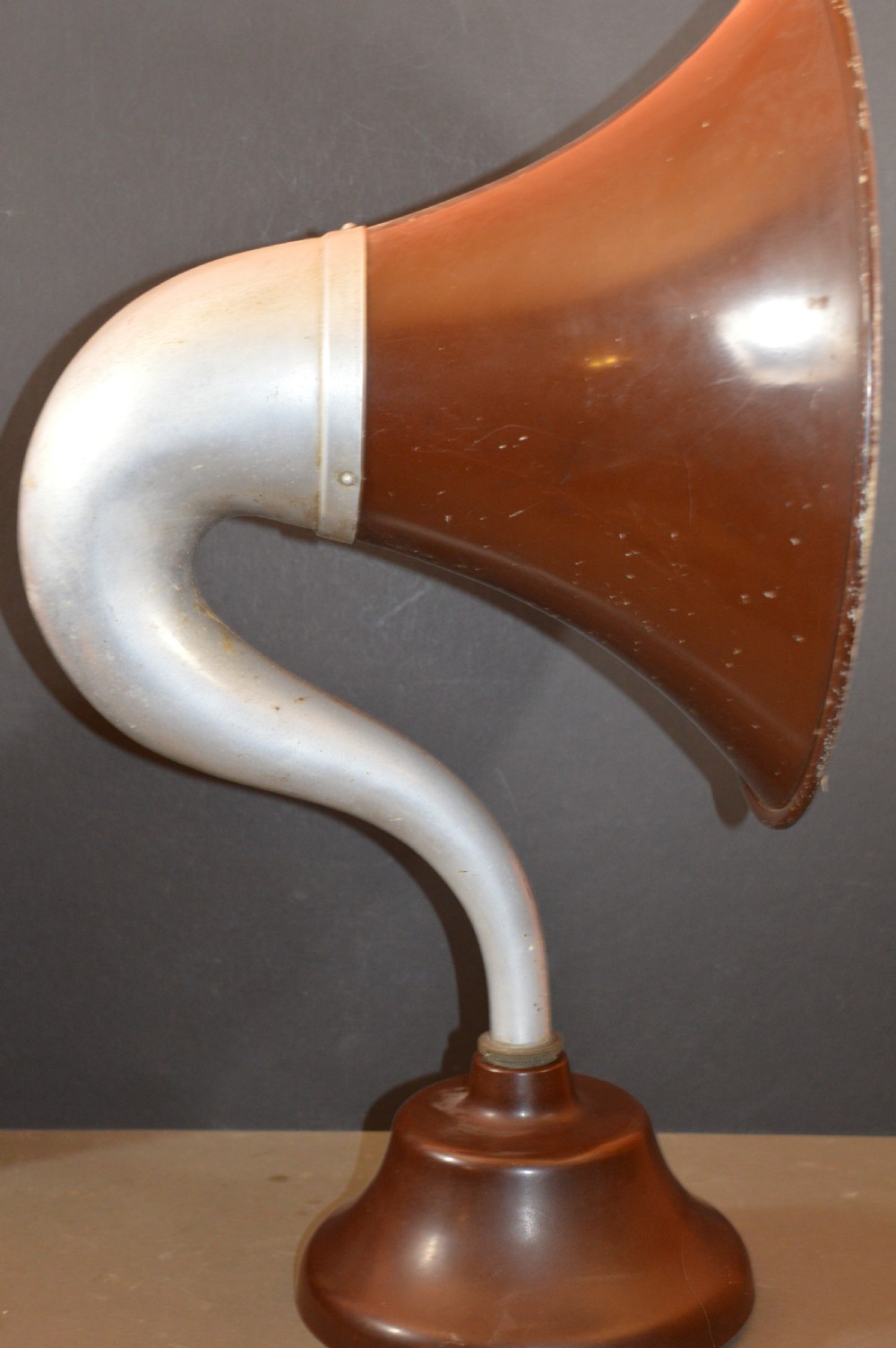 An antique 1930s British Thomson-Houston horn loudspeaker with a flared dark brown Bakelite bell, a curved silver metal neck, and a matching rounded Bakelite base. View IX