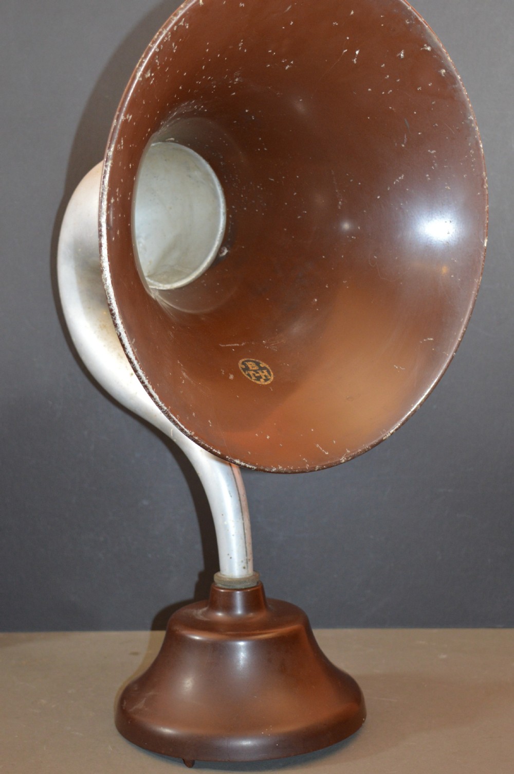 An antique 1930s British Thomson-Houston horn loudspeaker with a flared dark brown Bakelite bell, a curved silver metal neck, and a matching rounded Bakelite base. View X