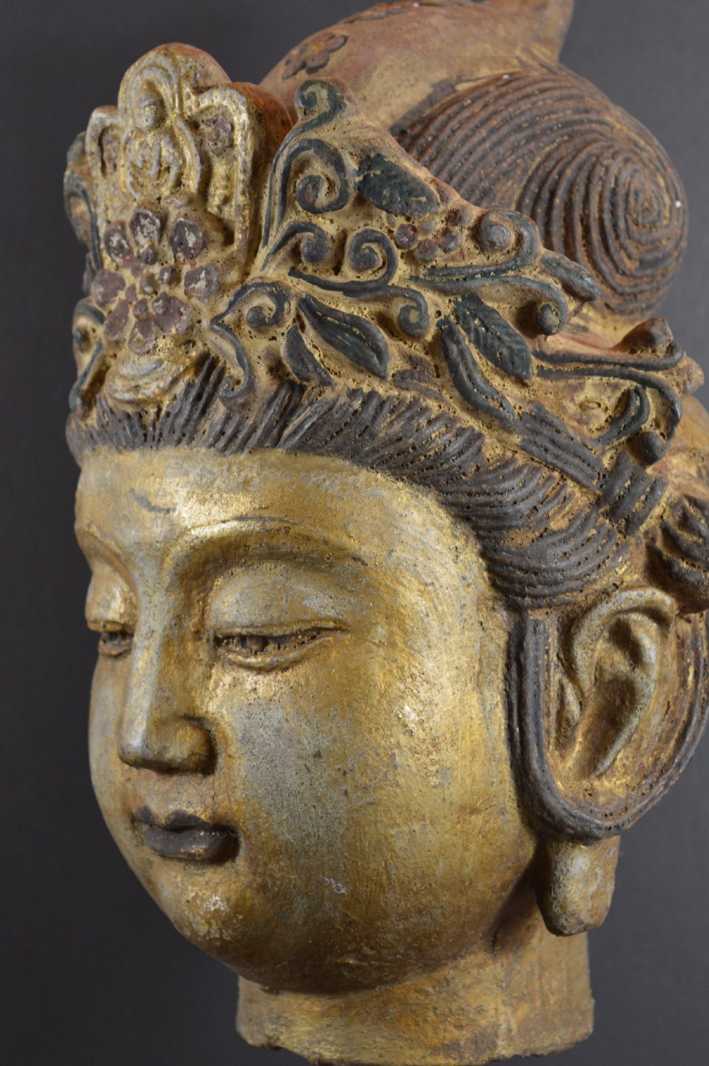 A late 19th-century cast iron head sculpture of Guanyin featuring detailed scrollwork tiara and residual gold gilding.