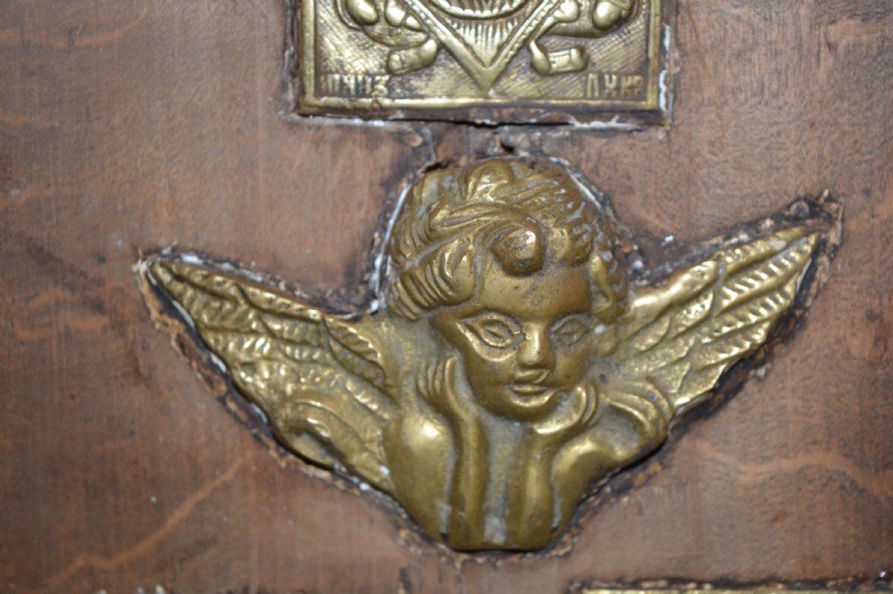 A rectangular wooden panel featuring three square brass Russian icons and a central relief of a winged angel head. View IV