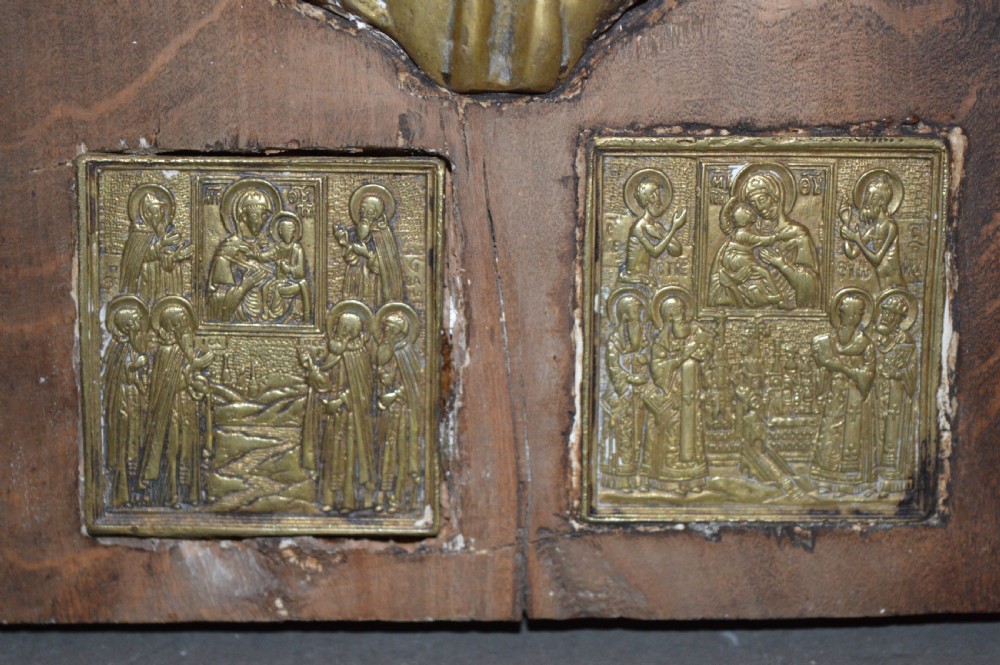 A rectangular wooden panel featuring three square brass Russian icons and a central relief of a winged angel head. View V