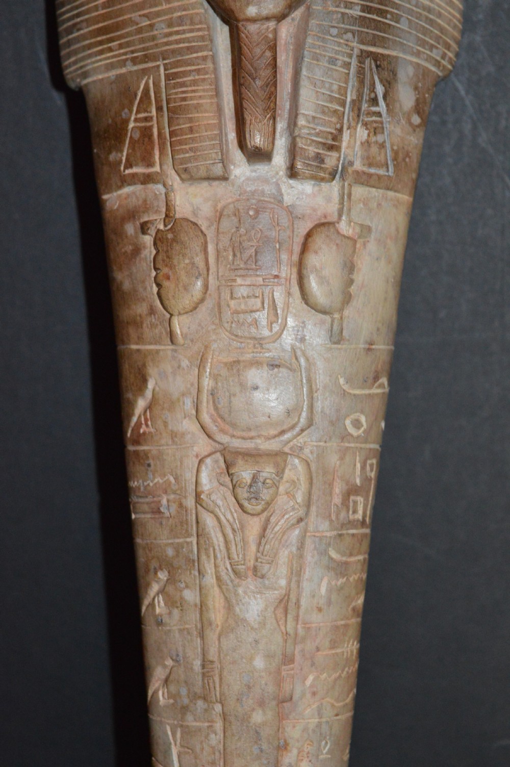A carved beige stone model of an Egyptian sarcophagus lid featuring a pharaonic face with a nemes headdress and hieroglyphic engravings. View III