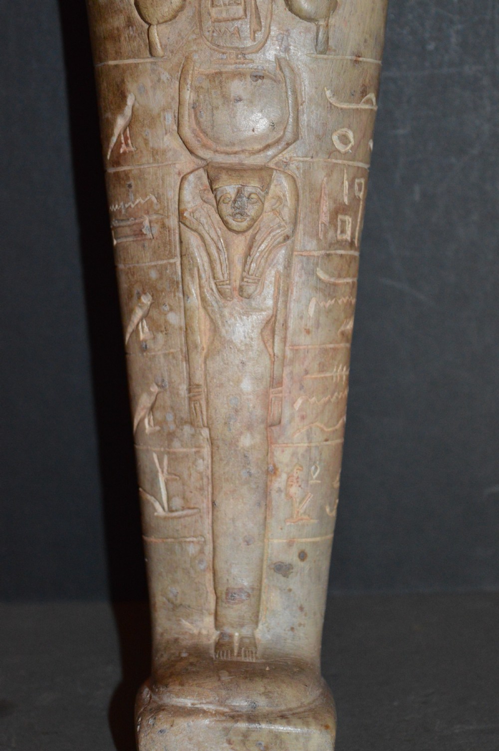 A carved beige stone model of an Egyptian sarcophagus lid featuring a pharaonic face with a nemes headdress and hieroglyphic engravings. View IV