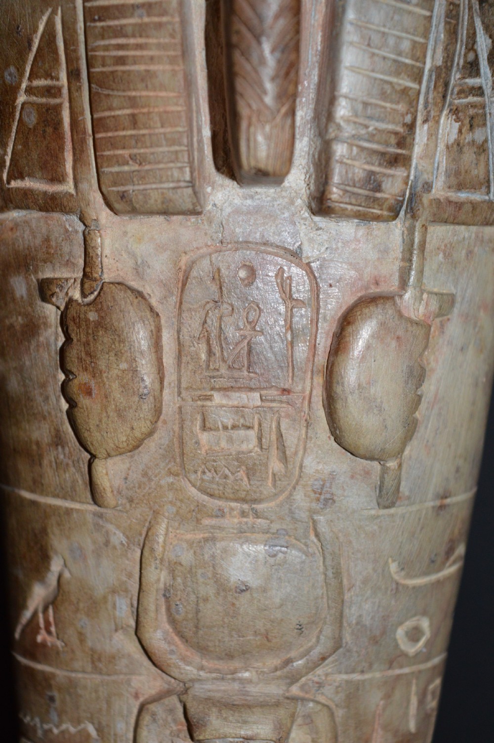 A carved beige stone model of an Egyptian sarcophagus lid featuring a pharaonic face with a nemes headdress and hieroglyphic engravings. View VII