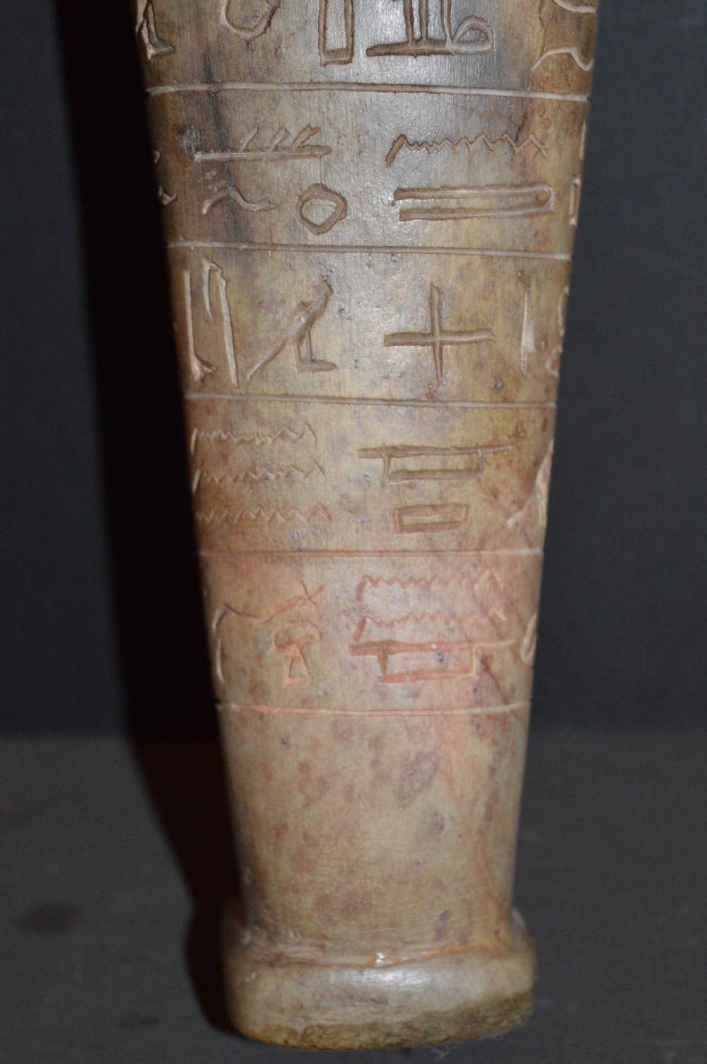 A carved beige stone model of an Egyptian sarcophagus lid featuring a pharaonic face with a nemes headdress and hieroglyphic engravings. View XI