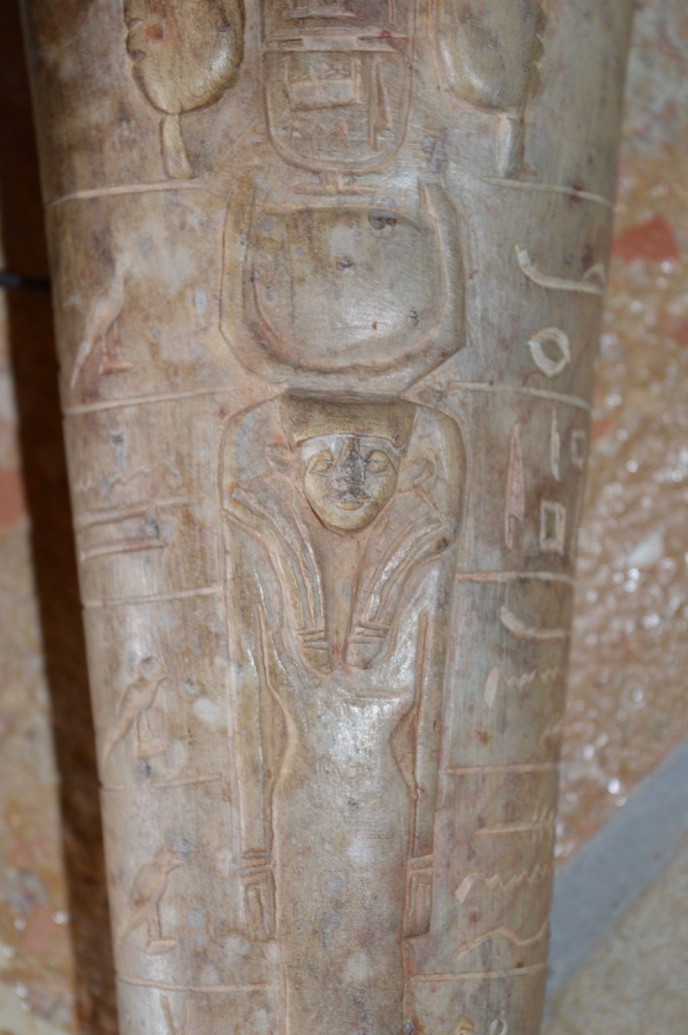A carved beige stone model of an Egyptian sarcophagus lid featuring a pharaonic face with a nemes headdress and hieroglyphic engravings. View XII