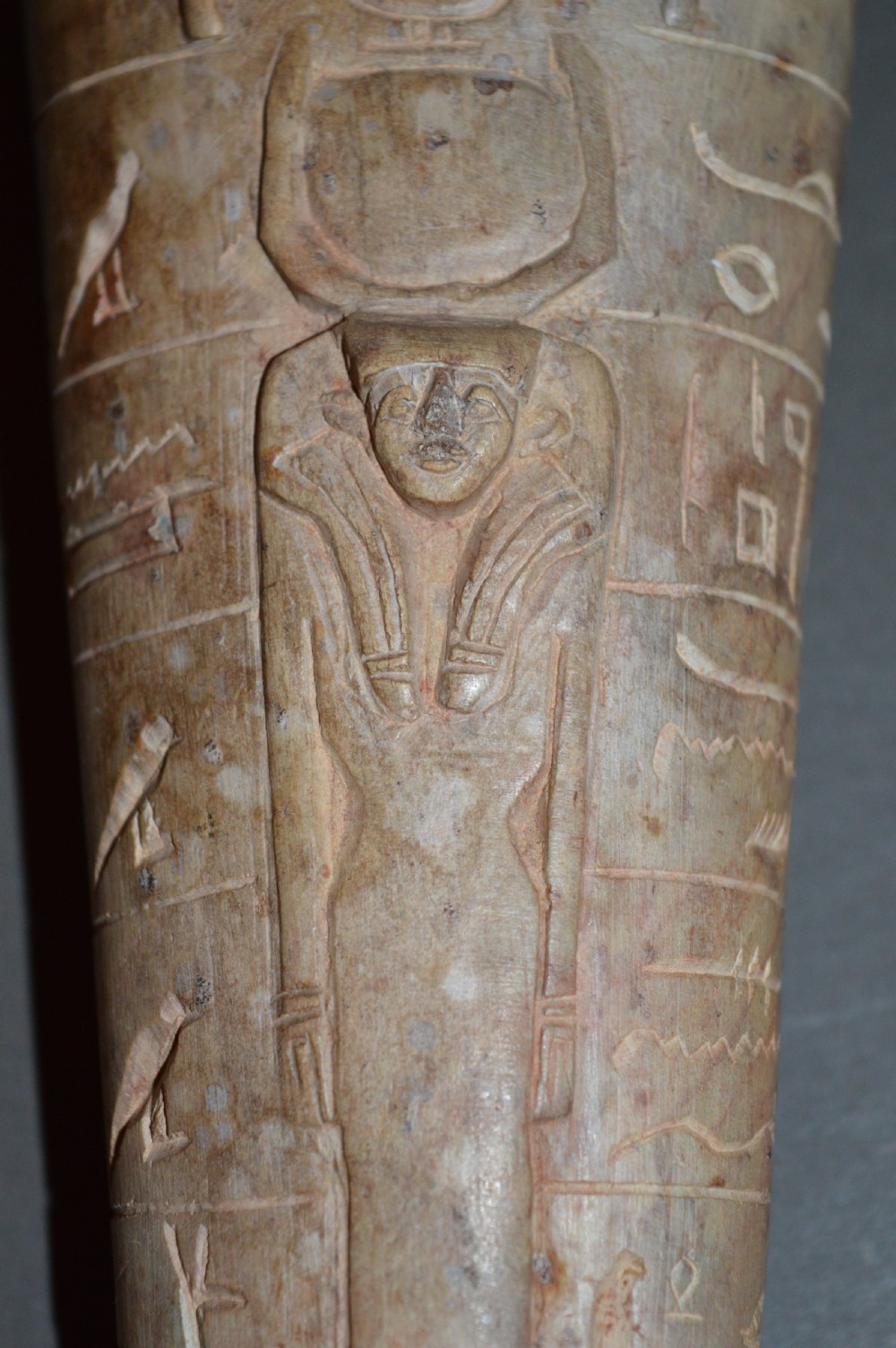 A carved beige stone model of an Egyptian sarcophagus lid featuring a pharaonic face with a nemes headdress and hieroglyphic engravings. View XIII