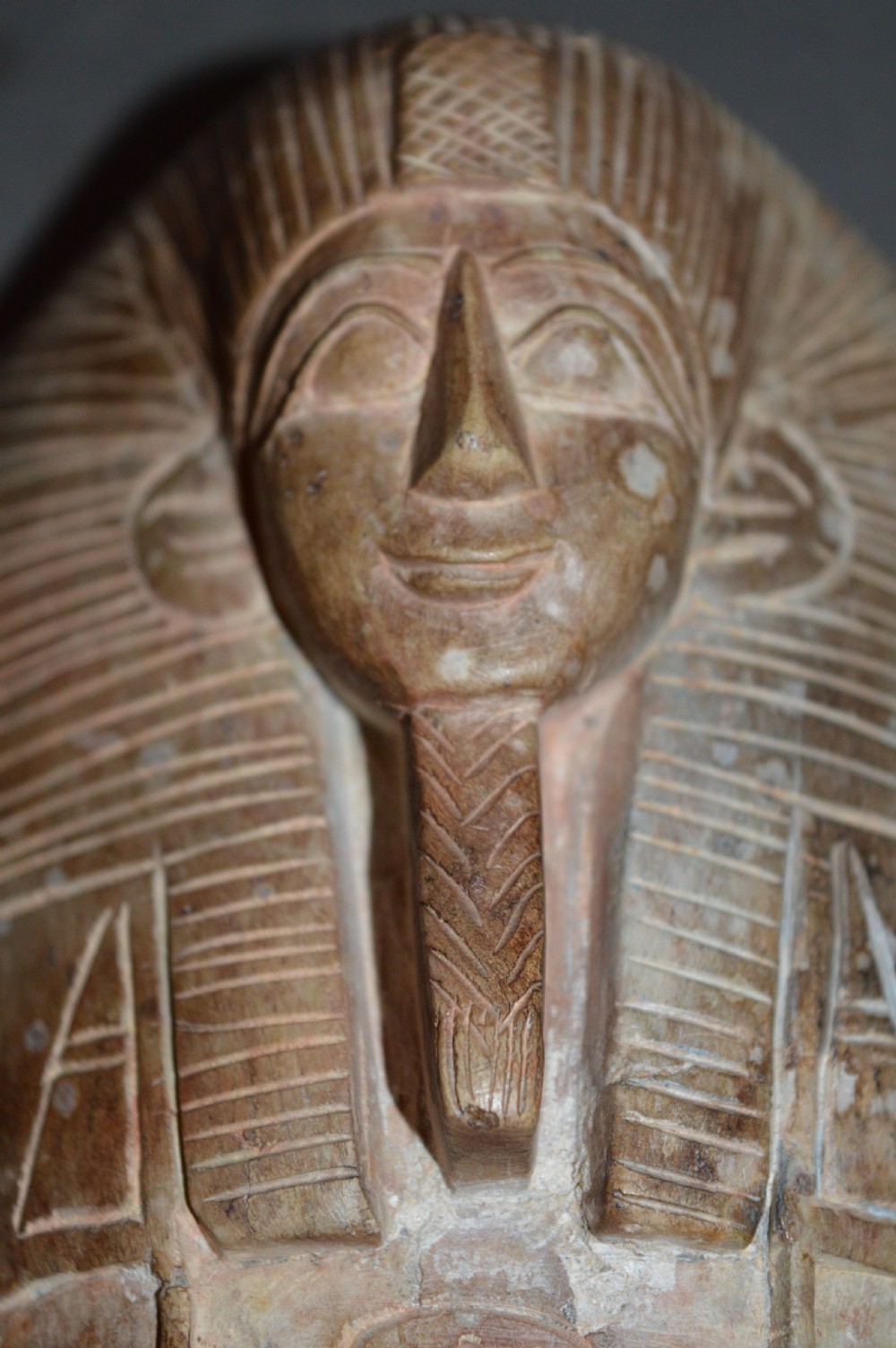 A carved beige stone model of an Egyptian sarcophagus lid featuring a pharaonic face with a nemes headdress and hieroglyphic engravings. View XIV