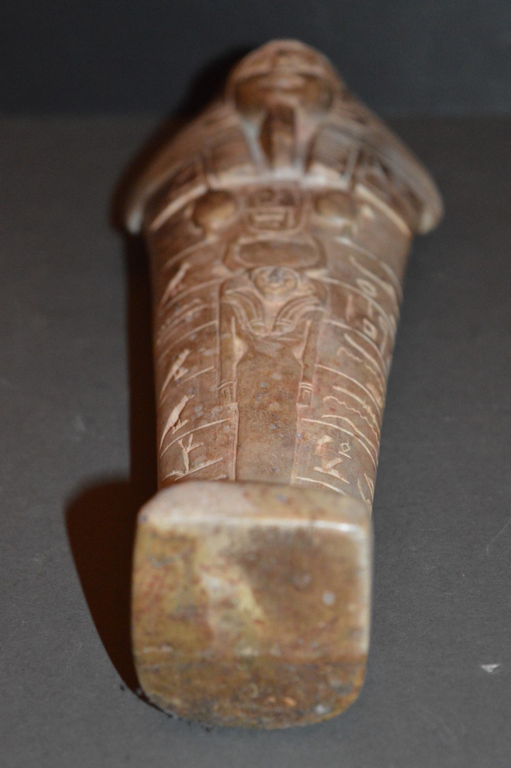 A carved beige stone model of an Egyptian sarcophagus lid featuring a pharaonic face with a nemes headdress and hieroglyphic engravings. View XV