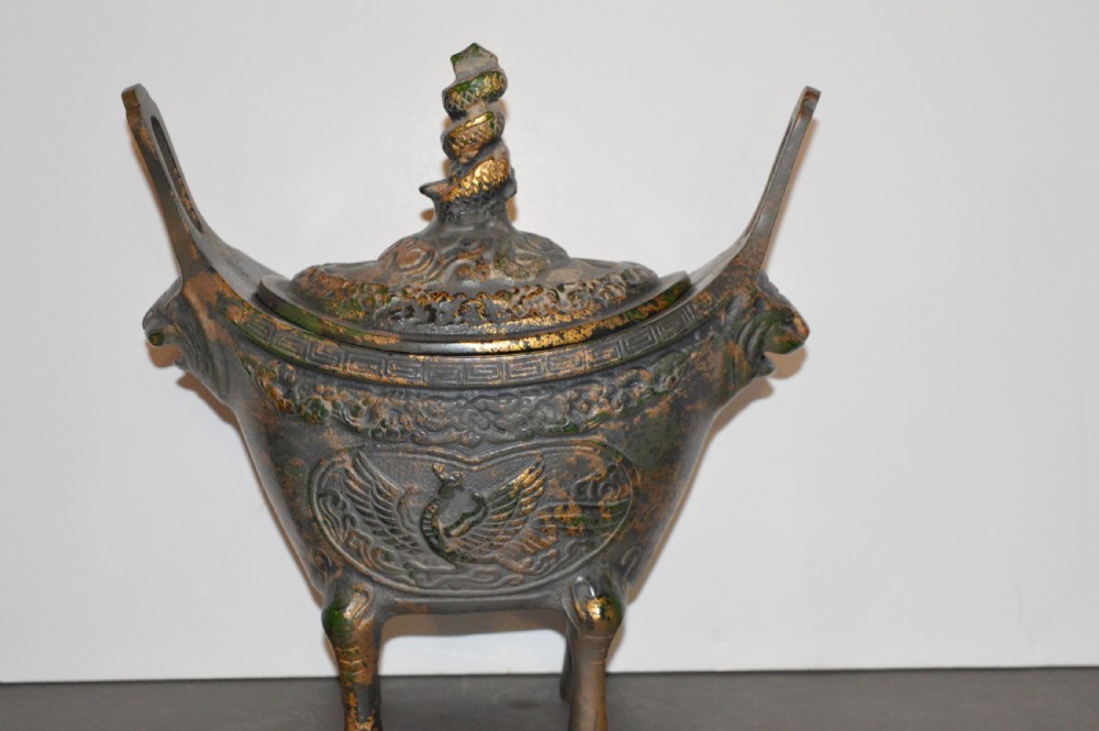 A late Qing dynasty dark parcel-gilt bronze censer featuring raised phoenix relief panels, extended vertical handles, and a serpent finial lid.