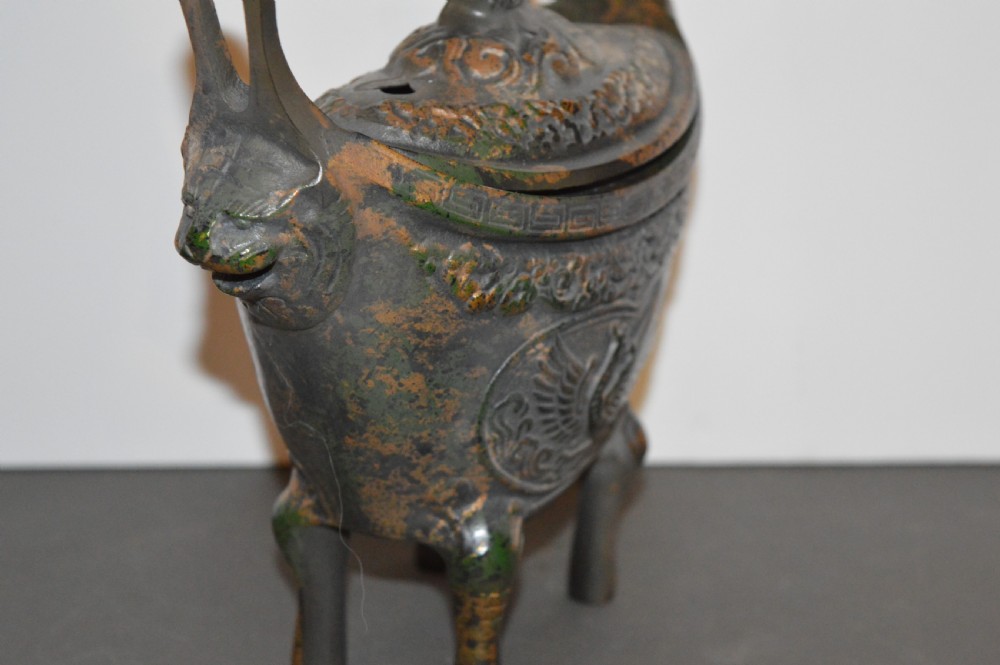 A late Qing dynasty dark parcel-gilt bronze censer featuring raised phoenix relief panels, extended vertical handles, and a serpent finial lid. View V