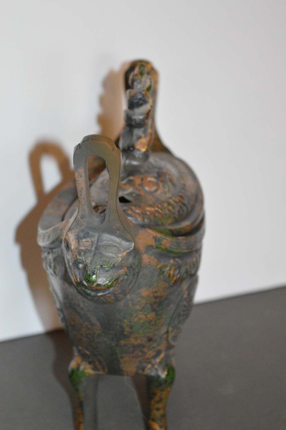 A late Qing dynasty dark parcel-gilt bronze censer featuring raised phoenix relief panels, extended vertical handles, and a serpent finial lid. View VI