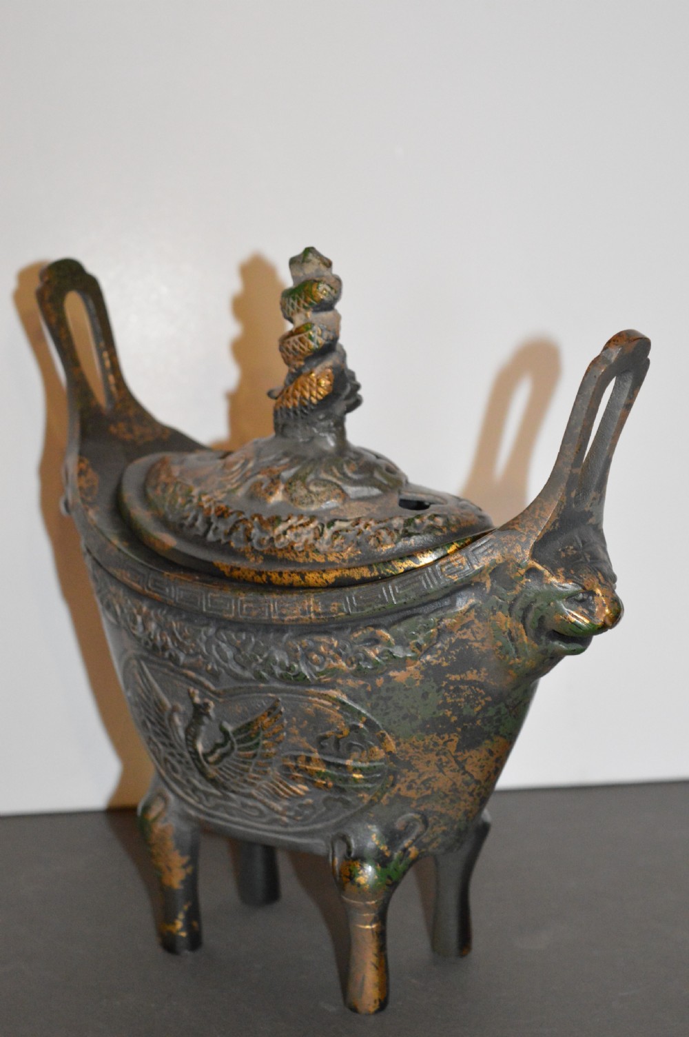 A late Qing dynasty dark parcel-gilt bronze censer featuring raised phoenix relief panels, extended vertical handles, and a serpent finial lid. View VII