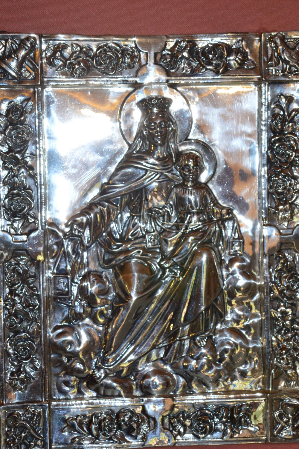A 1920s Spanish religious icon depicting the Madonna and Child in embossed silver-toned metal, set within a brown leather frame. View III