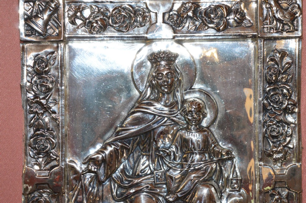 A 1920s Spanish religious icon depicting the Madonna and Child in embossed silver-toned metal, set within a brown leather frame. View V
