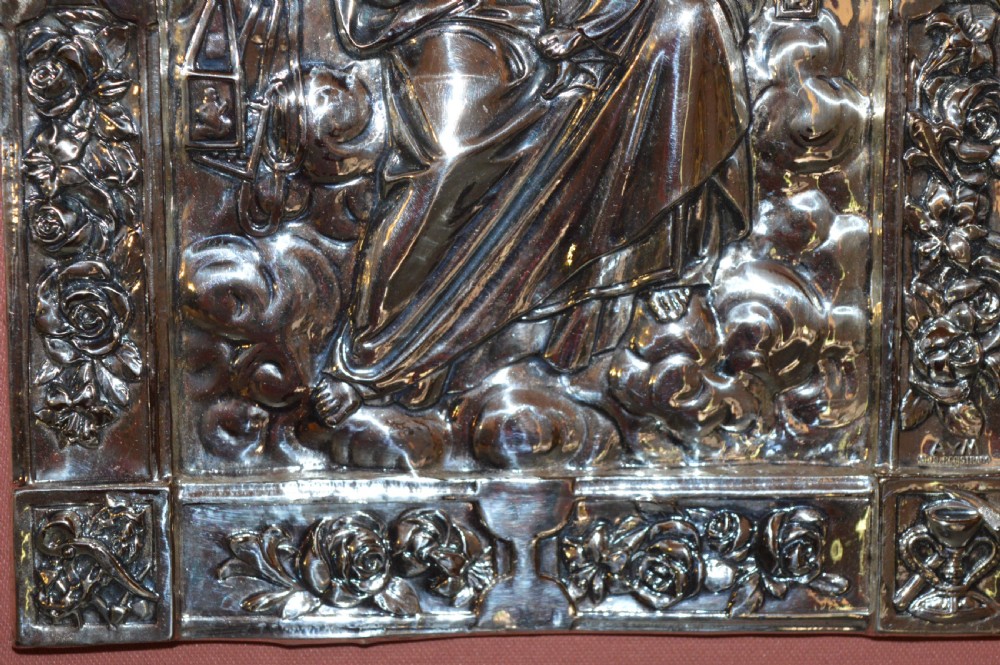 A 1920s Spanish religious icon depicting the Madonna and Child in embossed silver-toned metal, set within a brown leather frame. View VI
