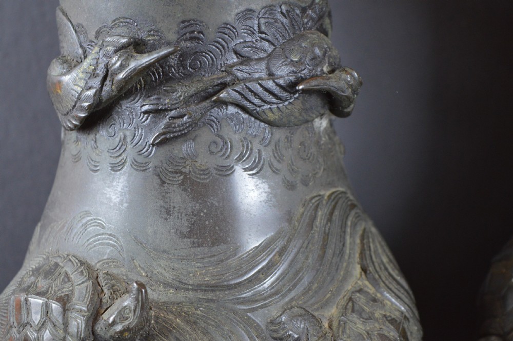 A pair of dark patinated Japanese bronze vases featuring high-relief carvings of flying birds and long-tailed turtles amongst stylised water waves. View V