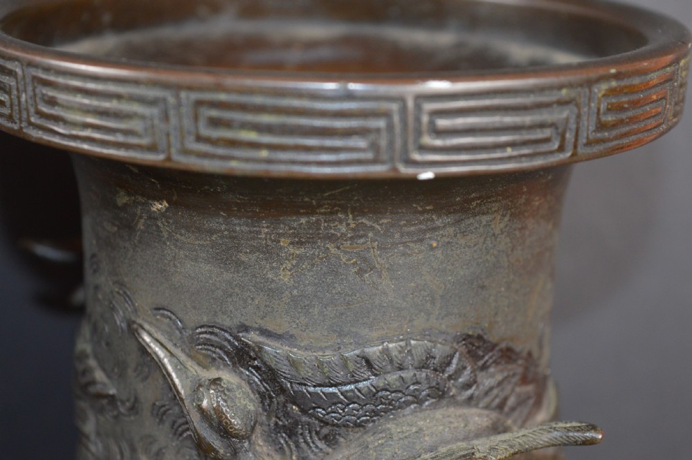 A pair of dark patinated Japanese bronze vases featuring high-relief carvings of flying birds and long-tailed turtles amongst stylised water waves. View X