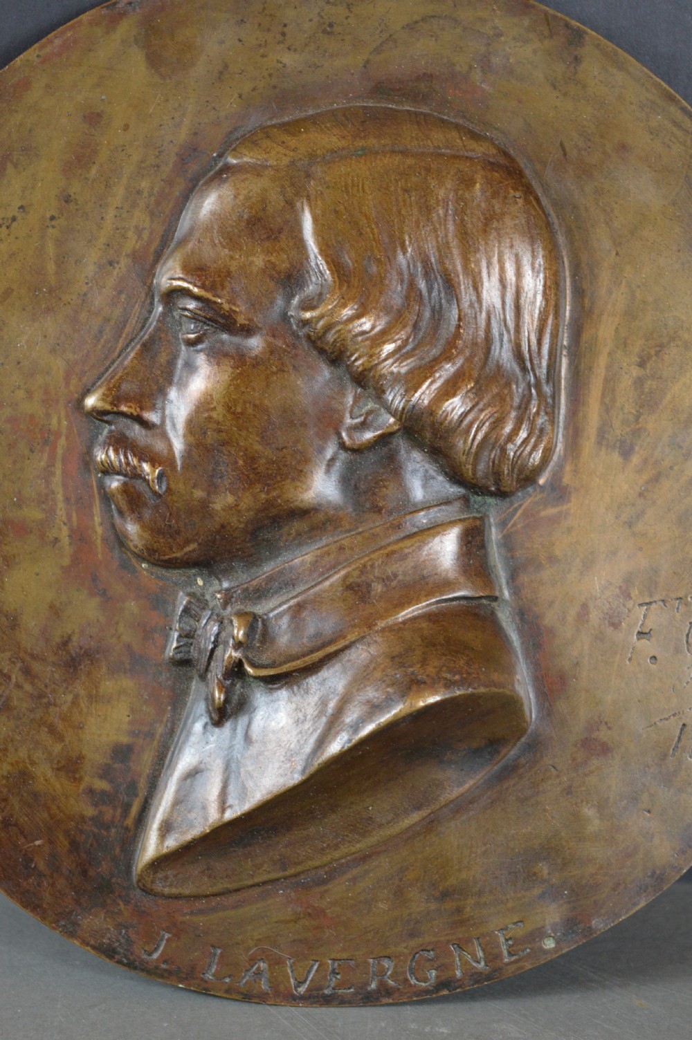 A circular patinated bronze relief plaque displaying a left-facing profile portrait of a man with a moustache, high collar, and bowtie, inscribed F George 1856. View II