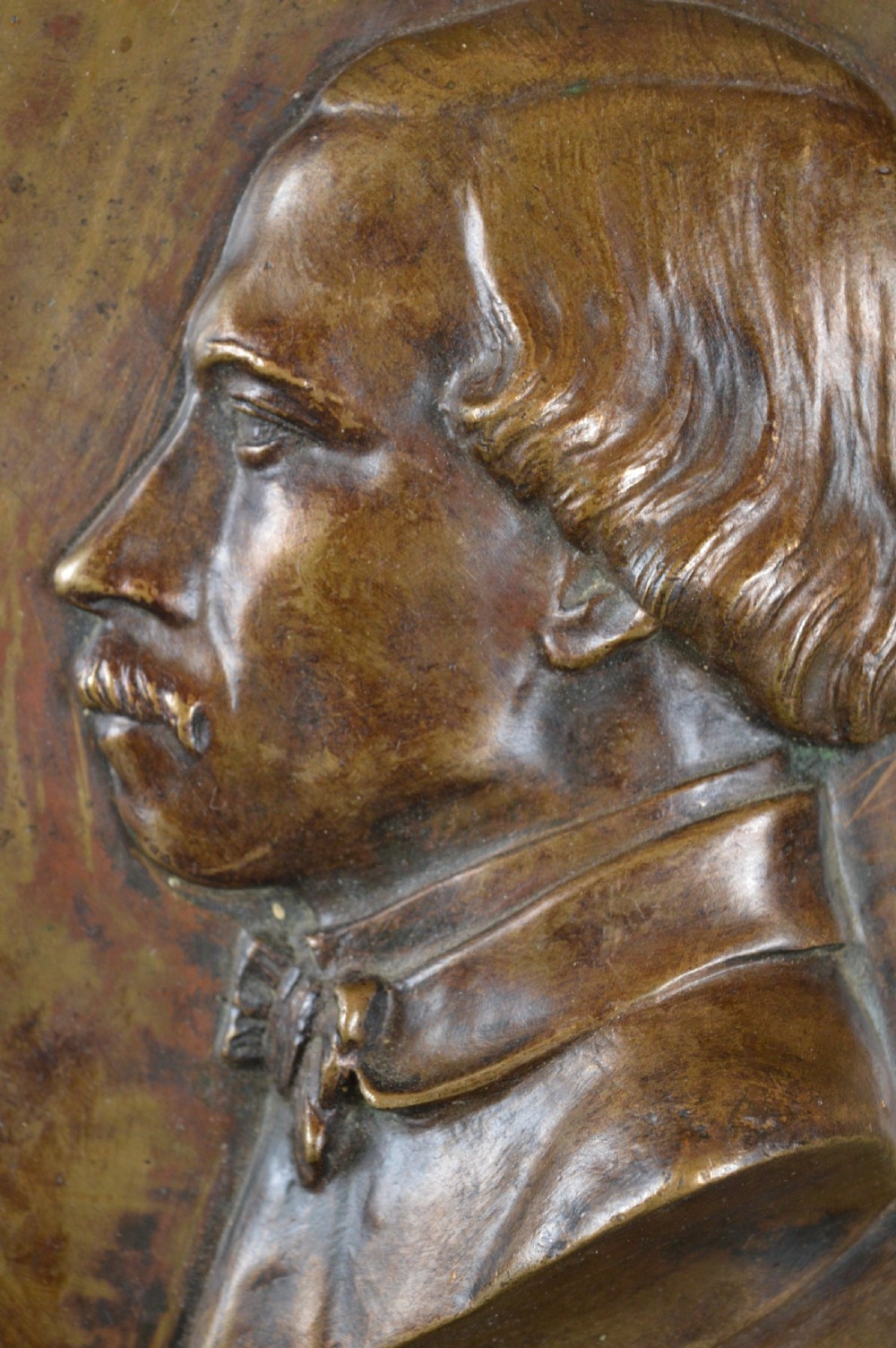 A circular patinated bronze relief plaque displaying a left-facing profile portrait of a man with a moustache, high collar, and bowtie, inscribed F George 1856. View III
