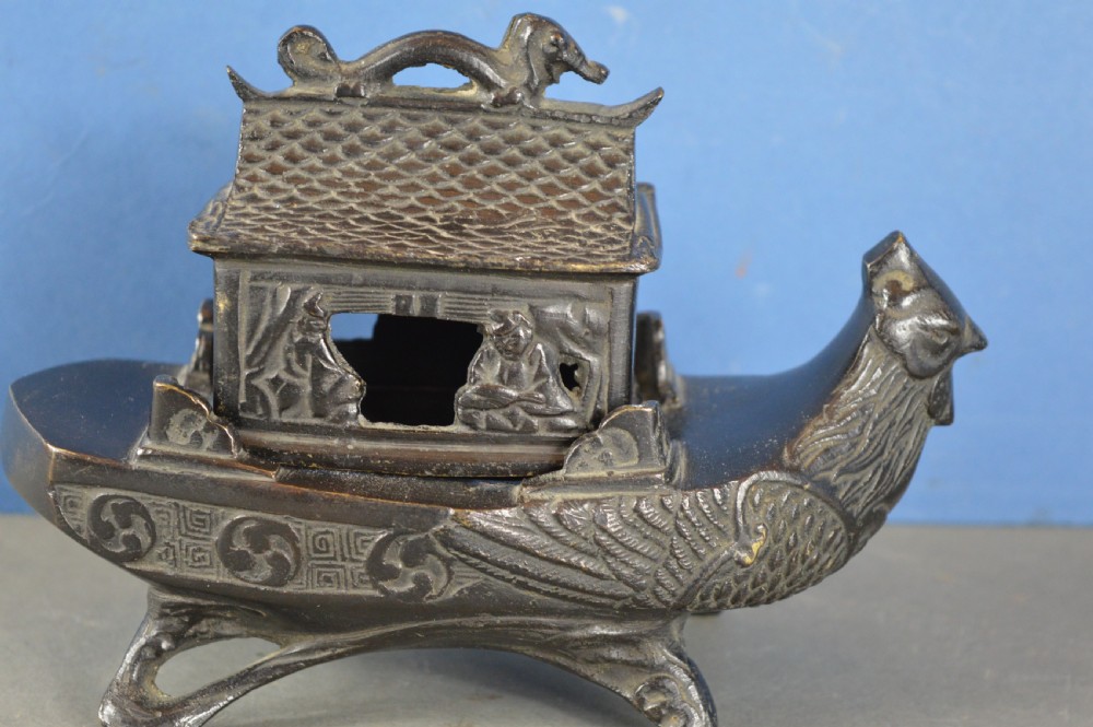 A dark patinated bronze Chinese censer cast in the form of a junk boat featuring a pagoda cabin, figure, and bird prow. View IX