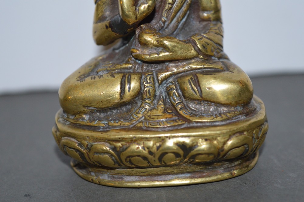 A 19th-century Tibetan bronze figure depicting a crowned seated Buddha in lotus position with a raised hand. View II