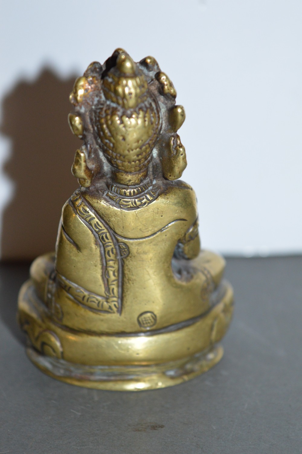A 19th-century Tibetan bronze figure depicting a crowned seated Buddha in lotus position with a raised hand. View V