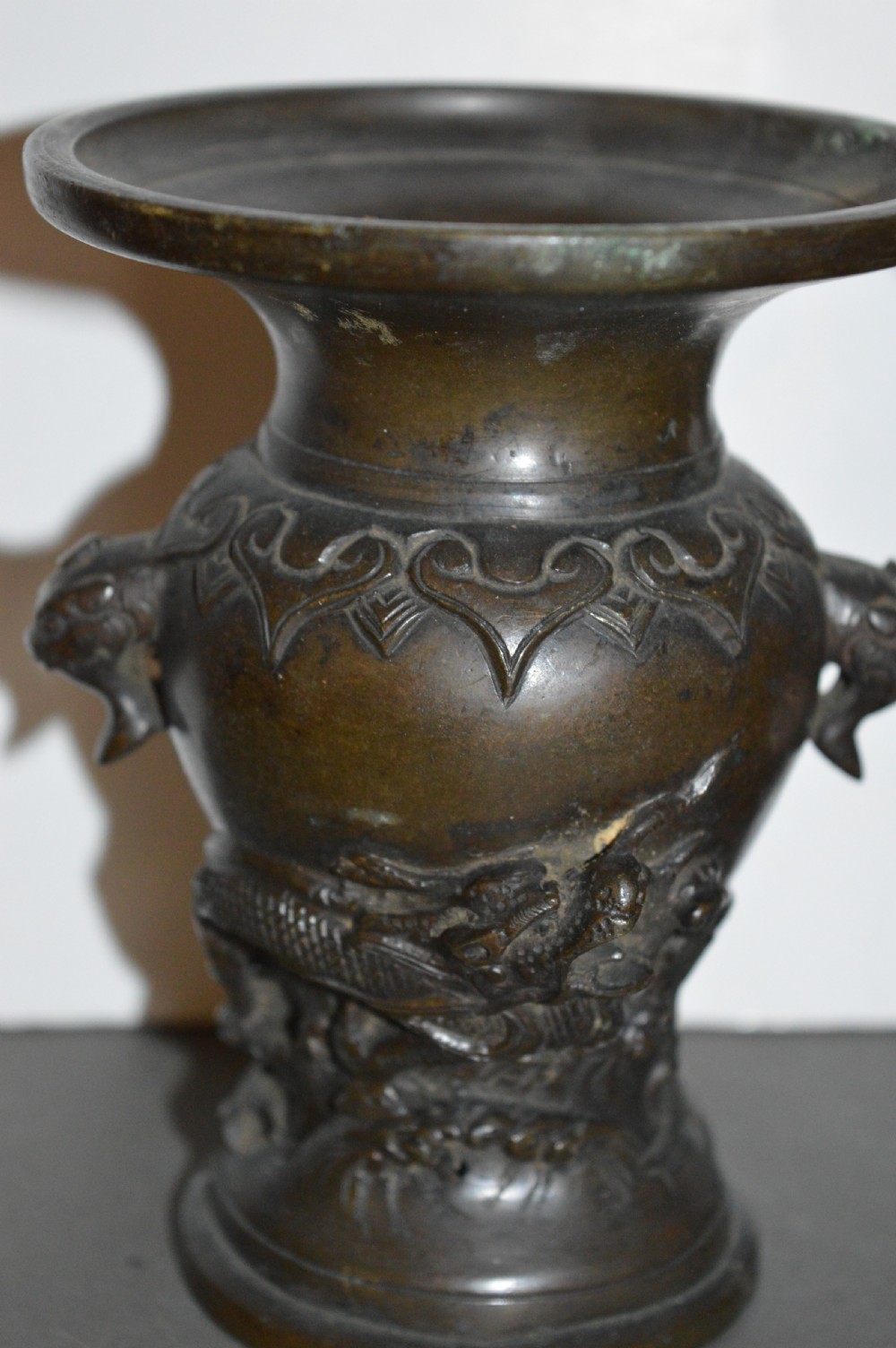 A pair of dark brown cast bronze Chinese vases featuring high-relief dragon motifs, beast head handles, and wide dished rims. View II