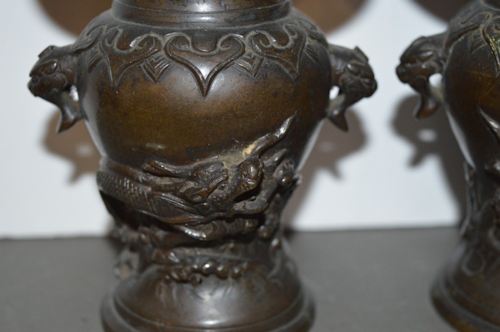 A pair of dark brown cast bronze Chinese vases featuring high-relief dragon motifs, beast head handles, and wide dished rims. View III
