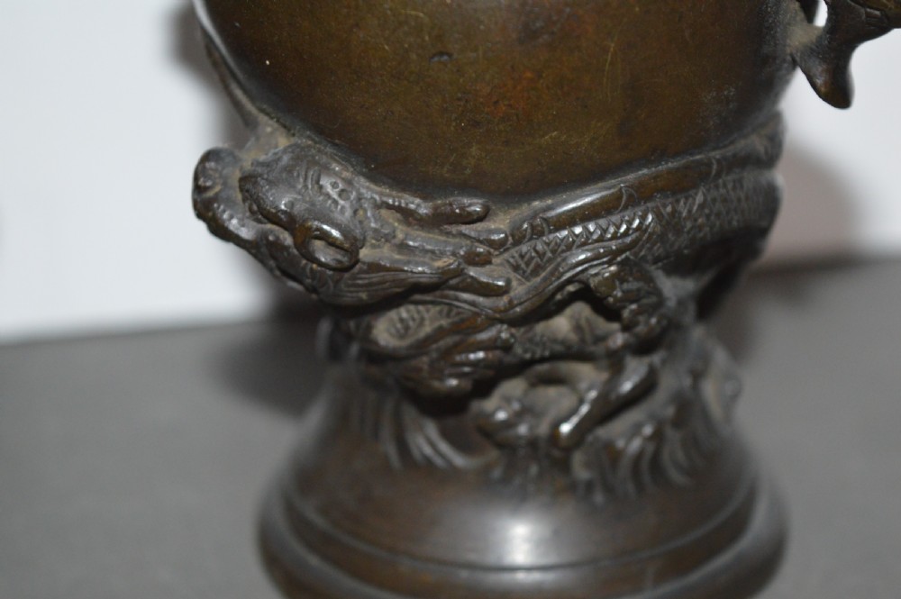 A pair of dark brown cast bronze Chinese vases featuring high-relief dragon motifs, beast head handles, and wide dished rims. View VI
