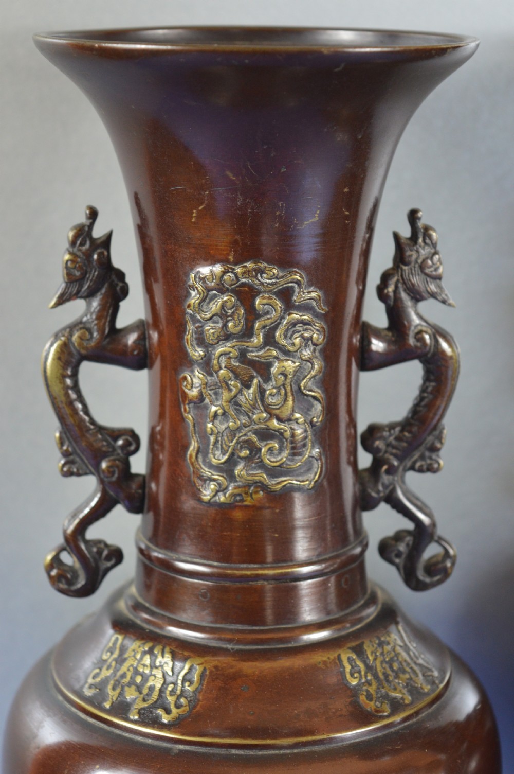 A pair of patinated dark brown Chinese bronze baluster vases with dragon handles and relief floral carvings. View II