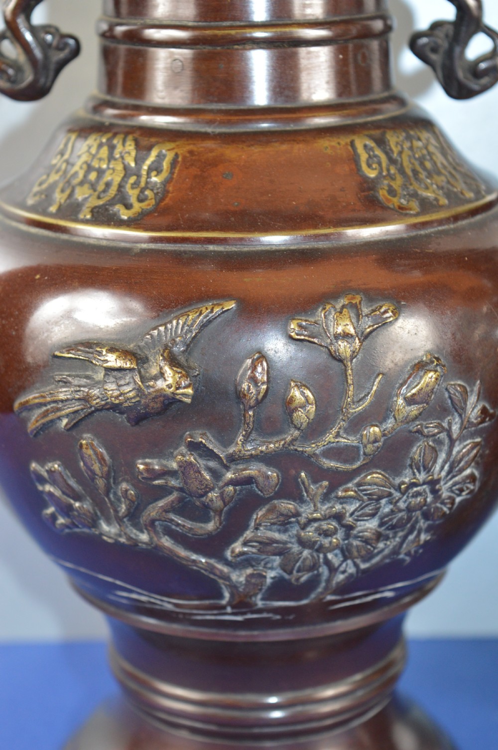 A pair of patinated dark brown Chinese bronze baluster vases with dragon handles and relief floral carvings. View III