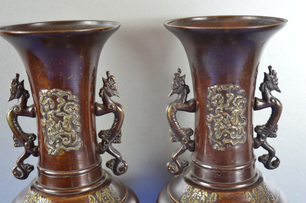 A pair of patinated dark brown Chinese bronze baluster vases with dragon handles and relief floral carvings. View IV