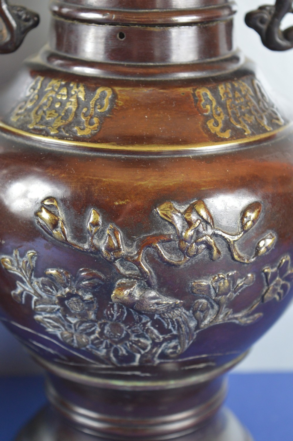 A pair of patinated dark brown Chinese bronze baluster vases with dragon handles and relief floral carvings. View VI