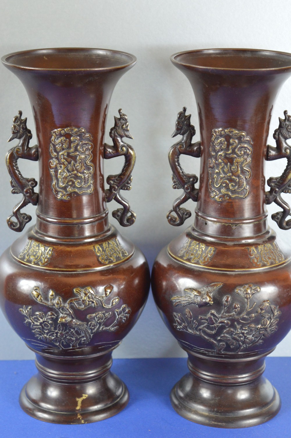 A pair of patinated dark brown Chinese bronze baluster vases with dragon handles and relief floral carvings. View VII