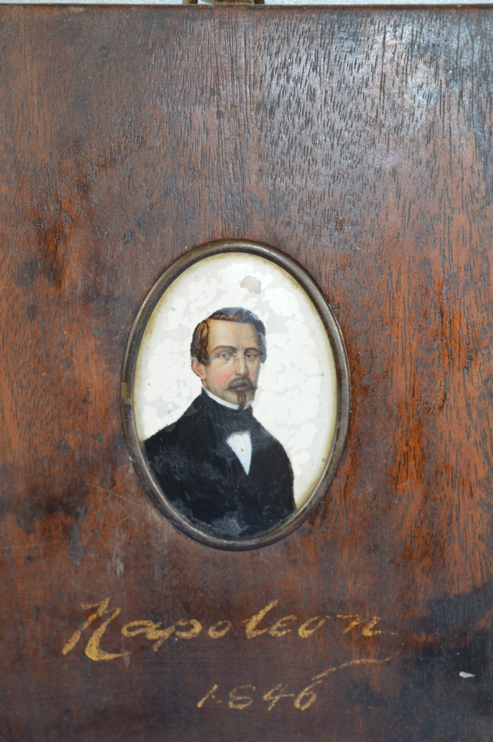 A pair of rectangular wooden plaque frames holding oval hand-painted portrait miniatures of Napoleon and Empress Eugenie within brass bezels. View II